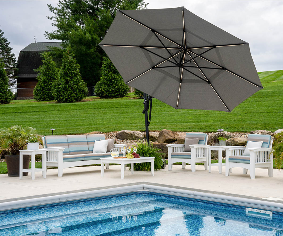 Poly vs. Wood Outdoor Furniture: Which Should You Choose? 8 White poly patio seating set beside a pool with umbrella