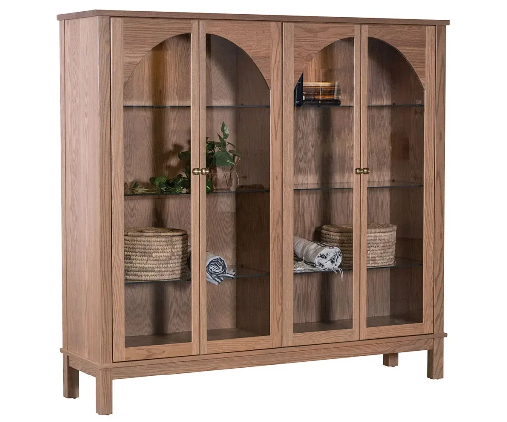 Tall wood display cabinet with glass doors, arched details, and interior shelving.